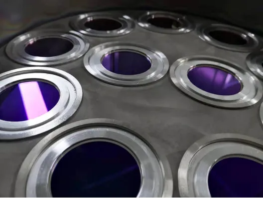 Optics loaded in a coating fixture, showing a violet anti-reflection tint